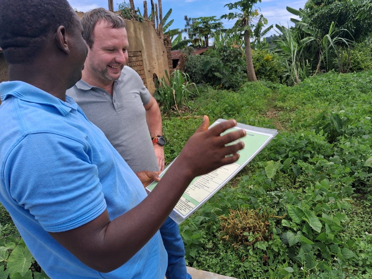 Lecture d'un plan sur le terrain au Burundi avec un agent de la CASOBU